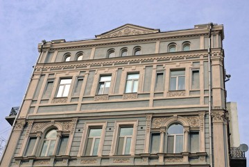 Fototapeta na wymiar gray facade of an old house with windows against a blue sky