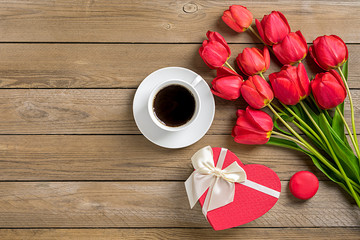 Row of red tulips and cup of black coffee americano on wooden background with space for text, message. Mother's Day, Hello spring, good morning concept. Card. Flat lay. Top view. Rustic style. 