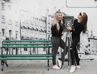 Obraz premium Happy friends having fun walking in city center. Beautiful young positive girls spend summer holidays. Two smiling pretty teenagers travel around old wonderful European city. Joint vacation concept