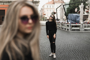 Happy friends having fun walking in city center. Beautiful young positive girls spend summer holidays. Two smiling pretty teenagers travel around old wonderful European city. Joint vacation concept
