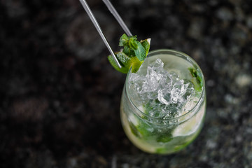 Mojito cocktail with lime and mint in highball glass on wooden table. Yellow background. Space for text