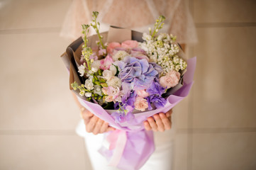 Woman holding a bouquet of tender light color violet spring flowers