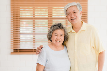 Asian elderly couple feeling happy smiling and looking to camera while relax in living room at...