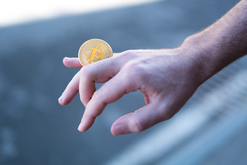 Cryptocurrency golden bitcoin coin. Man holding in hand symbol of crypto currency - electronic virtual money for web banking and international network payment, selective focus, toned