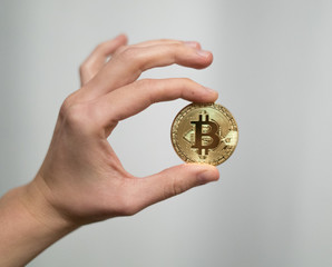 Fototapeta na wymiar Cryptocurrency golden bitcoin coin. Man holding in hand symbol of crypto currency - electronic virtual money for web banking and international network payment, selective focus, toned