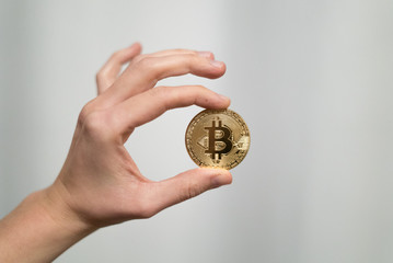 Plakat Cryptocurrency golden bitcoin coin. Man holding in hand symbol of crypto currency - electronic virtual money for web banking and international network payment, selective focus, toned