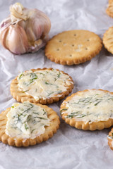 Crackers with smeared garlic butter with dill on white paper