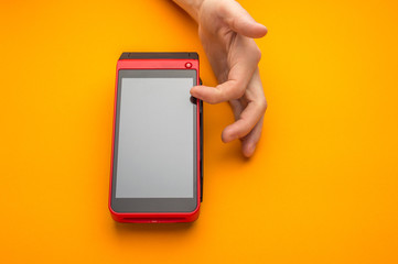Cashier fill payment information on touchscreen POS terminal. Customer contactless payments with nfc cards and gadgets in market. Closeup photo with orange background and copy space for text.