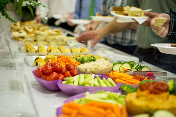 People serving from veggie tray