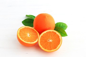 Orange fruit and one cut in half, with leaf isolated on white background.