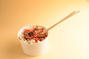 Paper cup with instant ramen noodles with beef and vegetables.