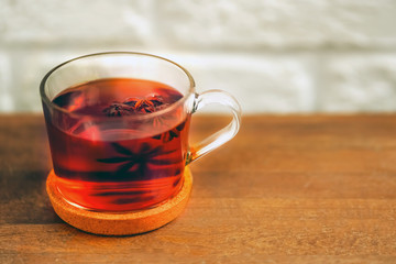 Glass cup of tea with badyan on a wooden table