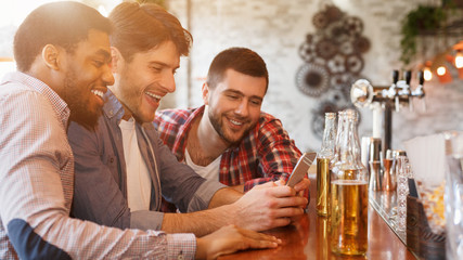Sharing News With Smartphone And Drinking Beer In Bar