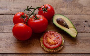 tomato branch with avocado on a wooden table with a buckwheat sandwich