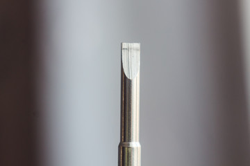 head of a metal flat screwdriver close-up on a blurred background. hand tool close up. copy space