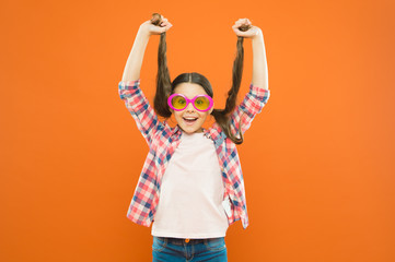 Because its your hair. Adorable girl holding ponytails hair on orange background. Small cute girl with long brunette hair wearing fancy glasses. Little hair model with beauty look