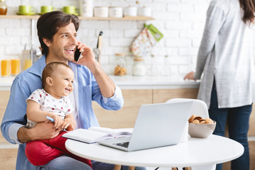 Father Working From Home On Laptop With Baby Son