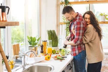 Young beautiful couple cooking together in their kitchen at home.