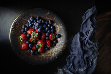 strawberries and blueberries in a metal bowl on the table