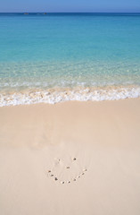 Smile Your On Vacation pebbles marking out a smiley face on a tropical beach