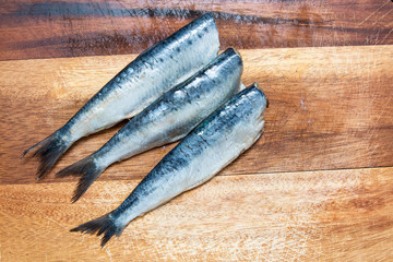fresh sardines on a wooden chopping board