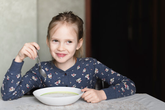 Portrait of smiling little girl eating oat meal