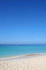Sandy tropical beach with waverunner in the distance, travel background