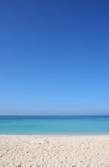 Fototapeta na wymiar Sandy tropical beach with turquoise sea and clear blue sky travel background