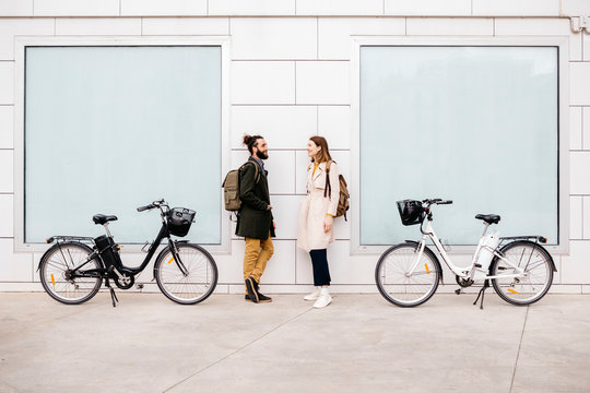Smiling couple with e bikes standing near wall