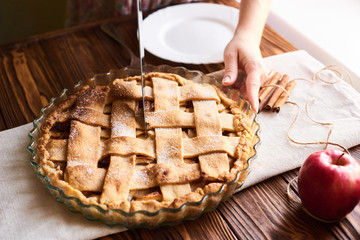 woman cutting a dessert of freshly baked apple pie on wooden the table
