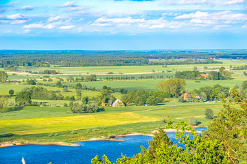 View over the Elbauen in Lower Saxony, Germany. You see a landscape with fields, meadows and the river Elbe under a blue sky with white clouds.