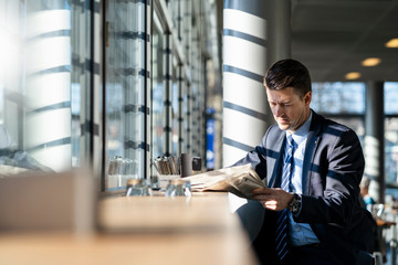 Businessman reading newspaper at the window in a cafe