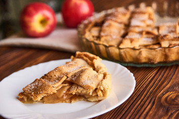 Eating sweet food context. Traditional holidays apple pie, slice on white plate and apples. Relishing sweet treats