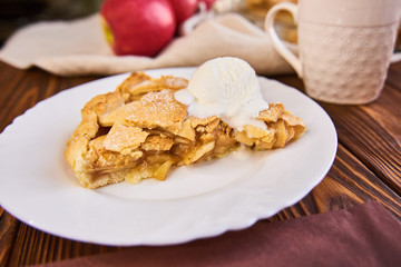 Tasty homemade apple pie, slice with ice cream. Apples. Plate, linen towel Wooden background Cup of...