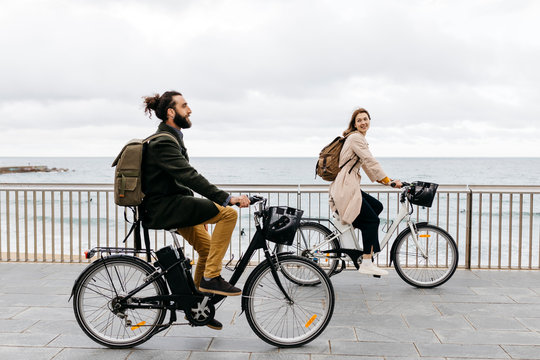 Couple riding e-bikes on beach promenade