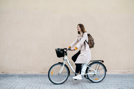 Woman riding e-bike along a wall