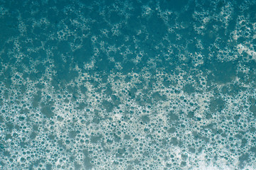Blue foam and soap bubbles on the water