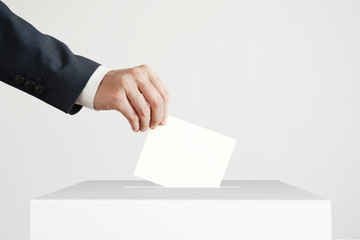 Man putting a ballot into a voting box.