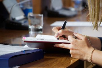 Fototapeta premium Hands of a young woman writing notes in a diary