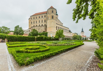 Mikulov, Czech Republic / South Moravia - May 28 2019: Mikulov castle with yellow and white facade standing on a rock, green lawn in a garden and sandy footpath. Grey overcast rainy day.