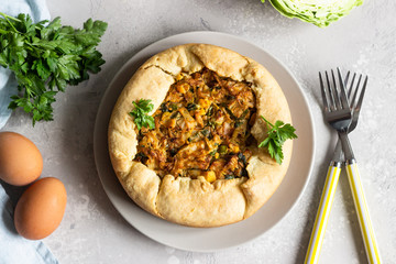 Pie with cabbage, eggs and parsley filling. Light stone background. 