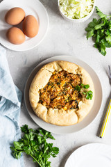 Pie with cabbage, eggs and parsley filling. Light stone background. 
