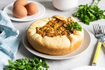 Pie with cabbage, eggs and parsley filling. Light stone background. 