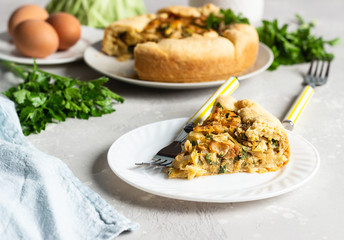 Pie with cabbage, eggs and parsley filling. Light stone background. 
