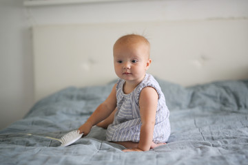 Bald Caucasian baby 10 months playing with comb