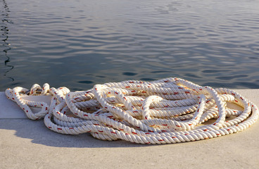 White rope on the stone dock by the sea for mooring boats or yachts