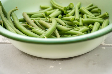 Freshly picked organic grean beans in a vintage enamel bowl on a white whashed table