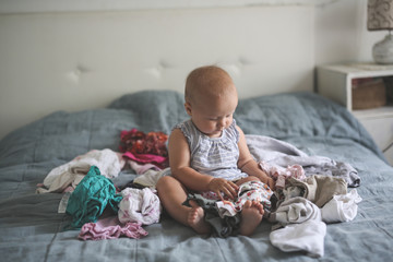 Funny Caucasian baby playing with bunch of clothes