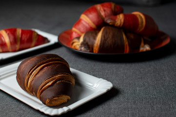 chocolate and red croissants lie on plates on a gray cloth, close-up buns