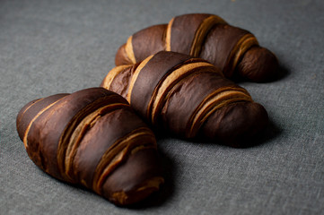 three chocolate brown croissants lying on a background
